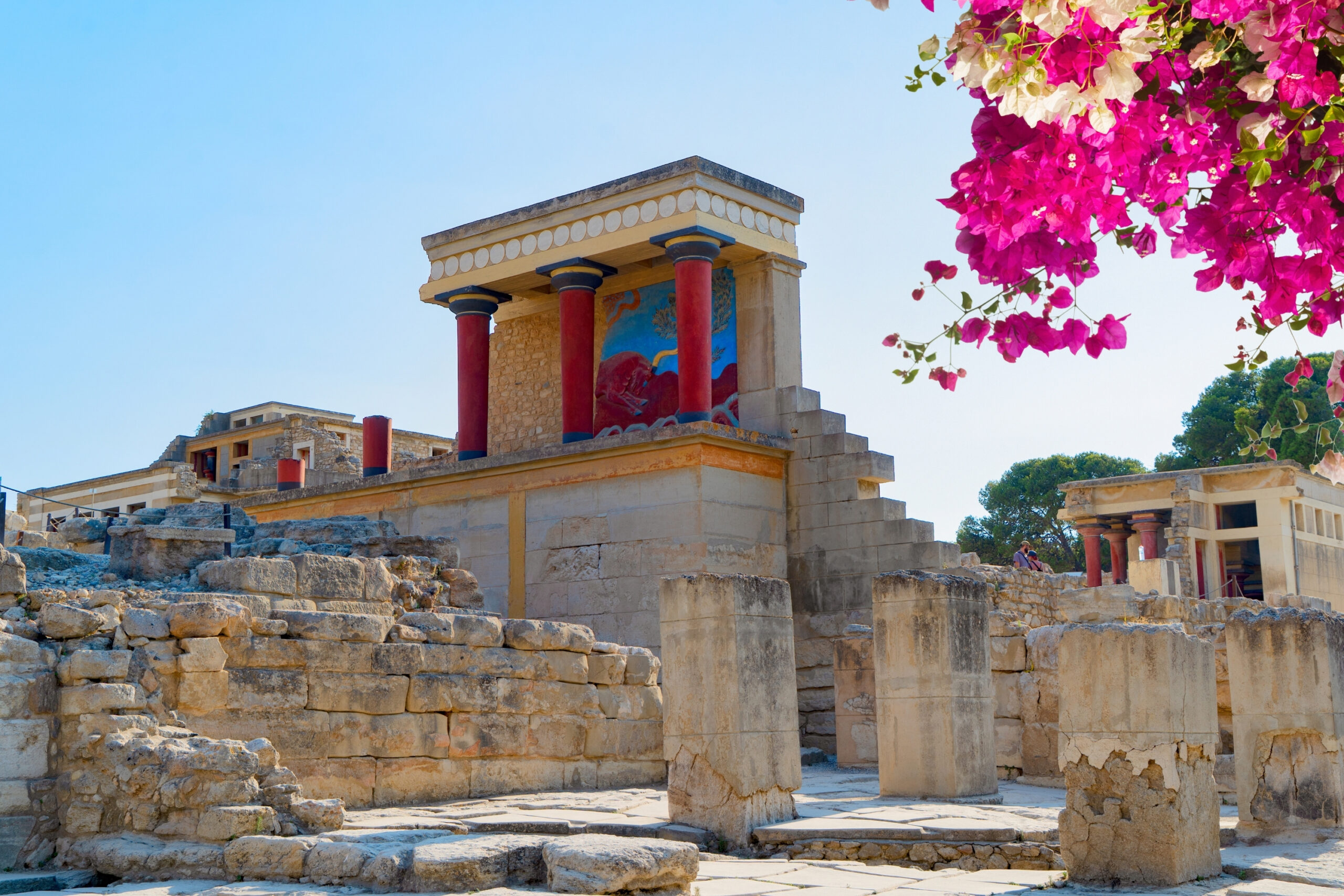 Ruinas del Palacio de Cnosos en Creta con columnas rojas minoicas y flores.