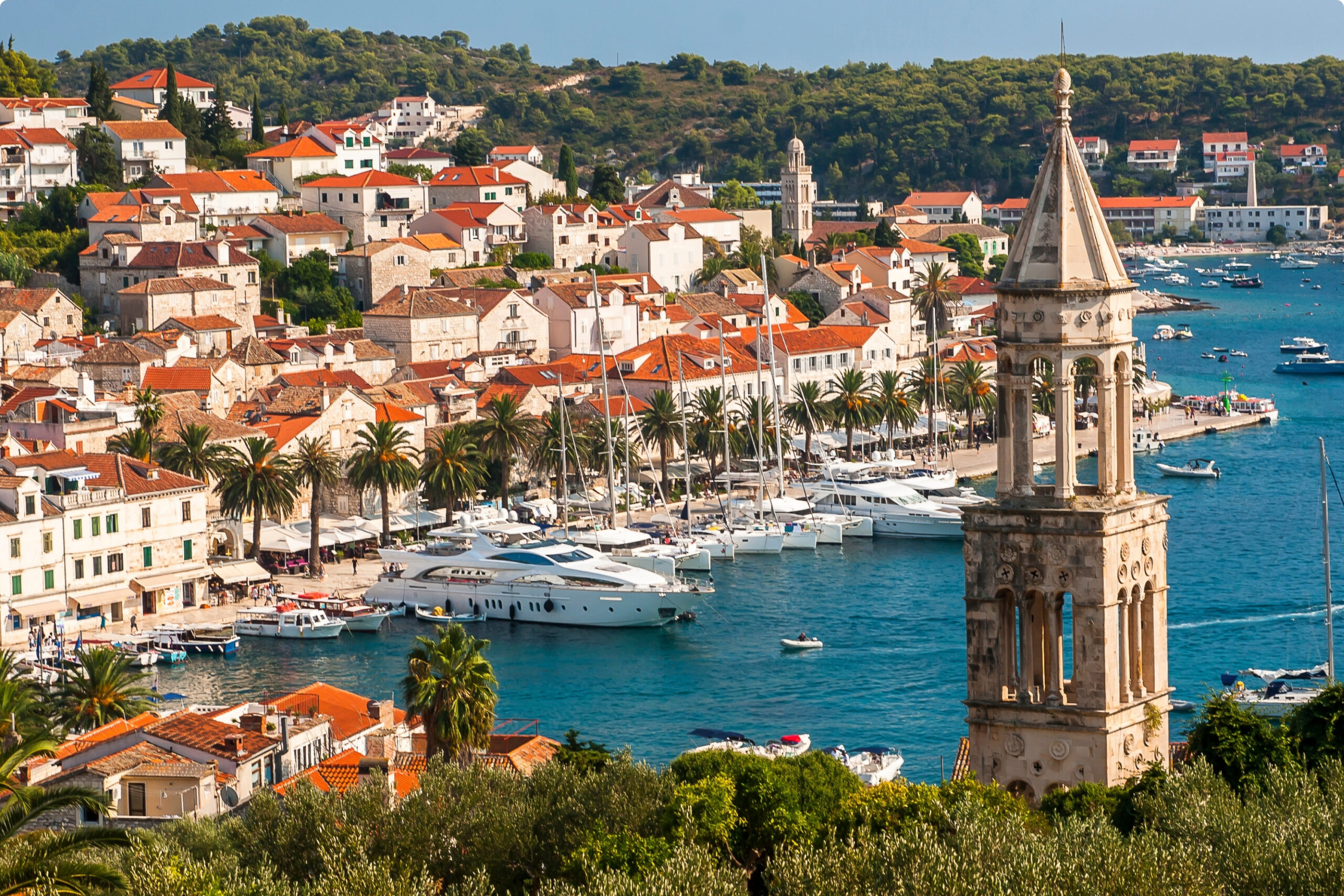 Ciudad costera de Hvar con campanario antiguo y yates amarrados en el mar Adriatico
